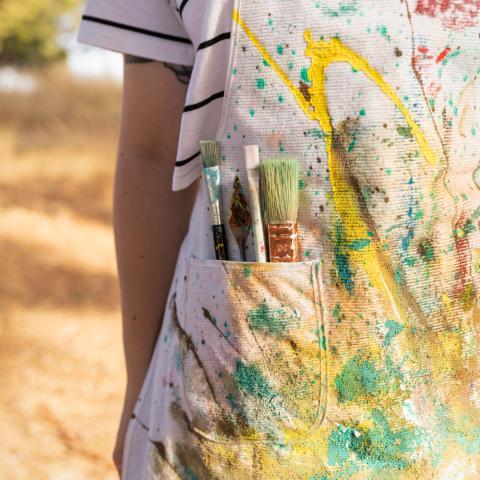 Personne avec tablier de peinture et pinceaux